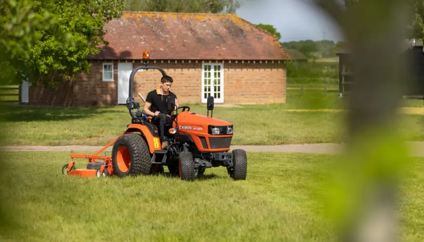 Mann fährt orangenen Kleintraktor mit Mähwerk. Welche Traktoren darf ich mit Klasse B fahren? Dieser hier ist klein genug.