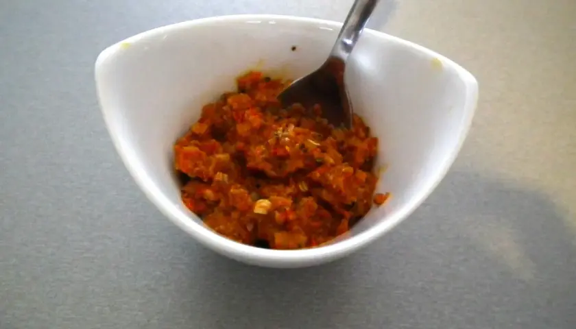 Czerwona pasta curry w białej miseczce z łyżką.