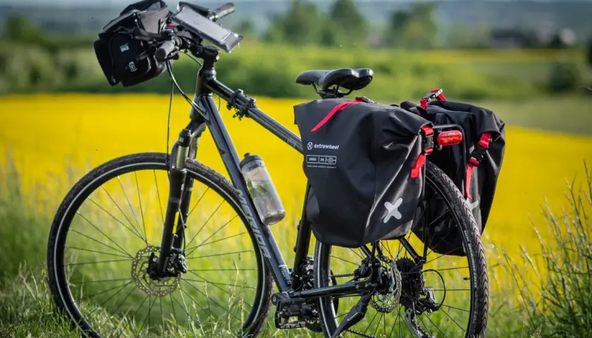 Rower z sakwami Extrawheel gotowy na wyprawę. Jakie sakwy rowerowe wybrać na długą trasę? Te czarne, wodoodporne, z czerwonymi akcentami, wyglądają na solidne.