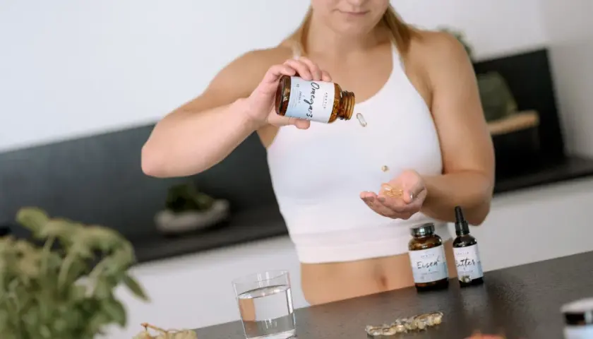 Frau nimmt Omega-3-Kapseln ein, um ihr Wohlbefinden zu fördern.
