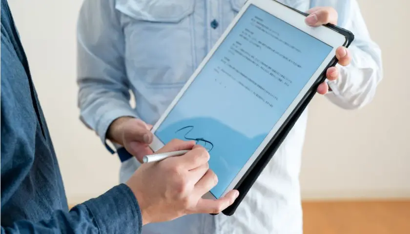 Firma electrónica en tablet, un hombre firma un documento digital con un stylus. El acto tiene pleno p.p. significado jurídico.