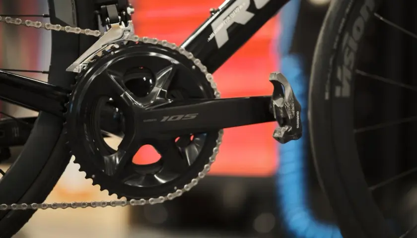 Czarna korba Shimano 105 z rowerowym łańcuchem i pedałem. Gotowa do jazdy po szosie.