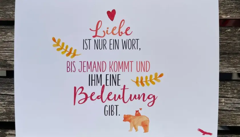 Eine Karte mit der Aufschrift "Liebe ist nur ein Wort, bis jemand kommt und ihm eine Bedeutung gibt." Ein Bärenbaby sitzt auf dem Rücken eines Bären.