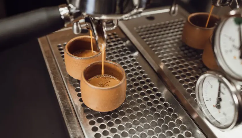 Zwei kleine Tassen werden mit Espresso gefüllt. Der Unterschied zwischen Café Crema und Kaffee Lungo wird hier deutlich: die Menge und die Crema.