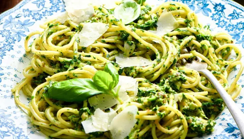 Pâtes au pesto, une recette italienne savoureuse avec des copeaux de parmesan et des feuilles de basilic frais.