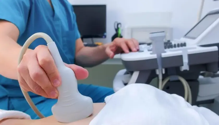 Lekarz wykonuje badanie USG, aby zbadać trzustkę pacjenta. Aparatura i sonda są widoczne.