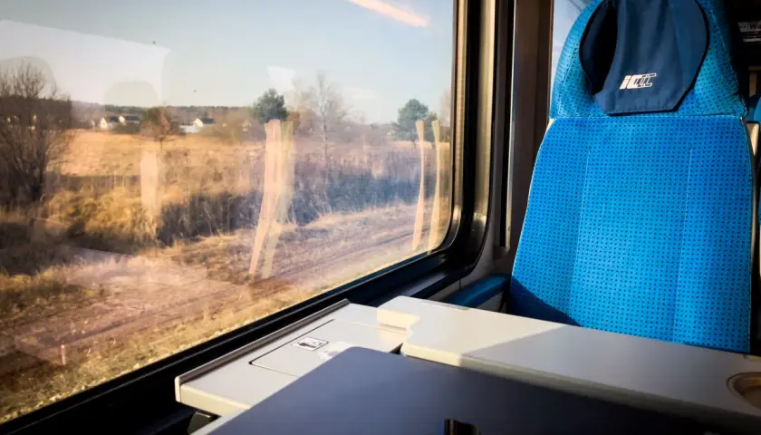 Widok z okna pociągu PKP, kiedy zmiana rozkładu jazdy PKP zaskoczyła pasażerów. Siedzenie w pociągu i krajobraz za oknem.
