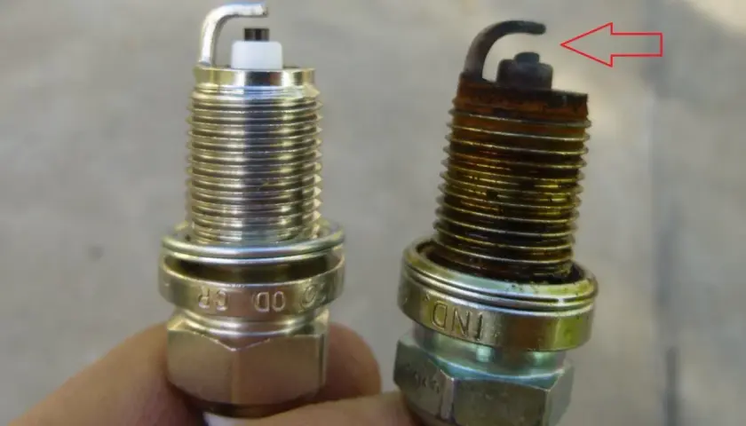 Una bujía nueva y otra desgastada, con óxido y el electrodo doblado. Así puedes saber si las bujías están mal.