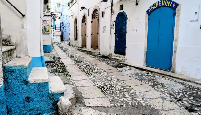 Urokliwa uliczka w Bari, z brukowanym chodnikiem i niebieskimi drzwiami. Idealne miejsce, by odkryć, co zobaczyć w okolicy.
