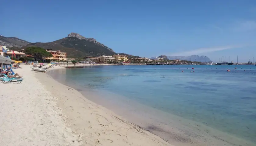 Plage de sable fin, eaux turquoise et montagnes en arrière-plan. Un rêve d'aranci in Sardegna.