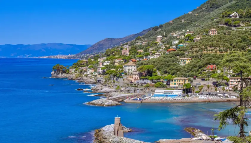 Vue pittoresque de la Riviera Italienne, avec des maisons colorées nichées sur une colline verdoyante surplombant la mer bleue.