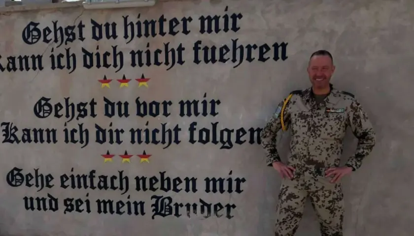 Ein Soldat der Bundeswehr steht vor einer Wand mit inspirierenden Bundeswehr Zitaten. "Gehe einfach neben mir und sei mein Bruder.