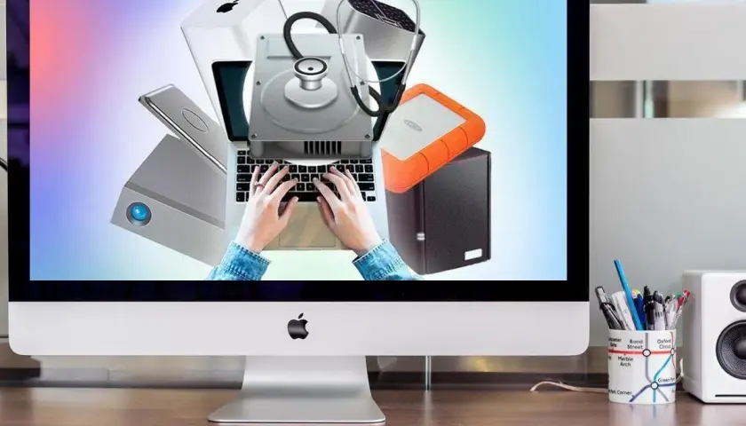 Festplatte wird nicht erkannt? Diagnose mit Stethoskop auf Laptop-Tastatur. Externe Laufwerke und Apple-Produkte im Hintergrund.