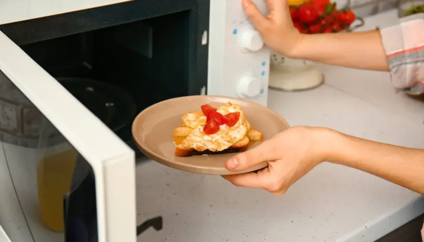 Piatto con toast, uova e pomodorini appena sfornati dal microonde.