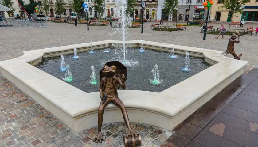 Żaba z parasolką siedzi przy fontannie na rynku w Bielsku-Białej.