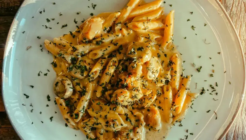 Penne w kremowym sosie z kurczakiem i pieczarkami, posypane natką pietruszki. Pyszny makaron, z którego jest zrobiony, zachwyca smakiem.