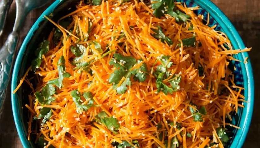 Ein erfrischender eiskraut salat aus geraspelten Karotten, garniert mit Koriander und Sesam.