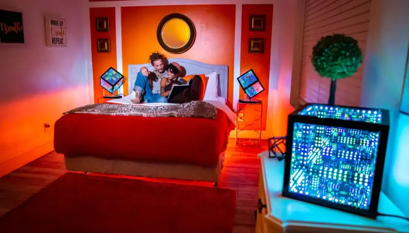 Pareja en cama iluminada por luces LED. Cada color de las luces LED tiene un propósito: rojo para pasión, azul para calma, verde para energía.