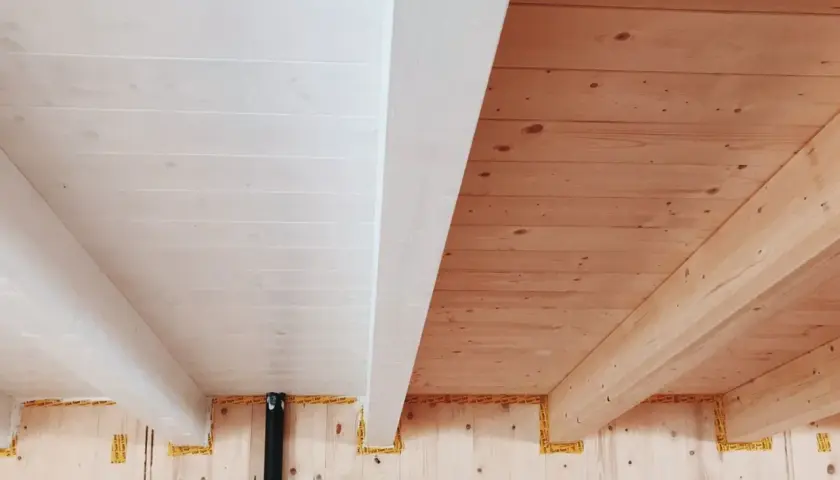 Soffitto con perline in legno sbiancato e travi a vista in legno naturale.