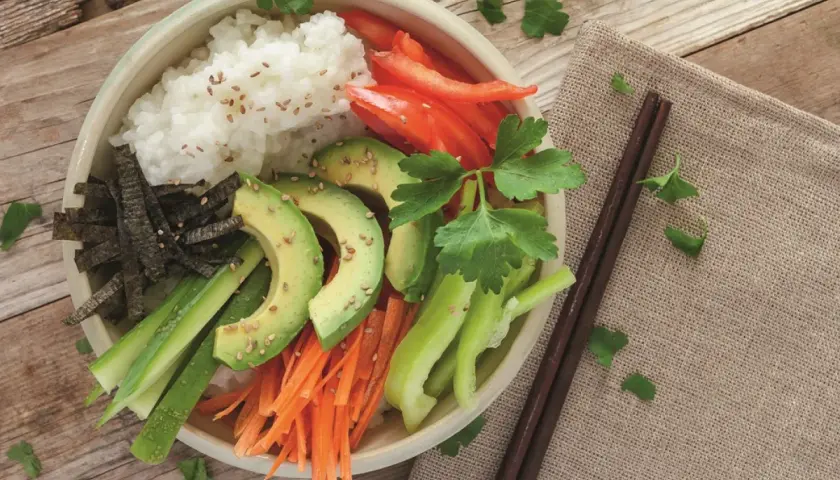Bunte vegane Sushi Bowl mit Reis, Avocado, Karotten, Gurke, Paprika und Nori. Ein gesunder Genuss!