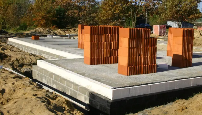 Budowa fundamentów pod dom. Stosy pustaków ceramicznych czekają na użycie. Zastanawiasz się, ile kosztuje fundament pod ogrodzenie?