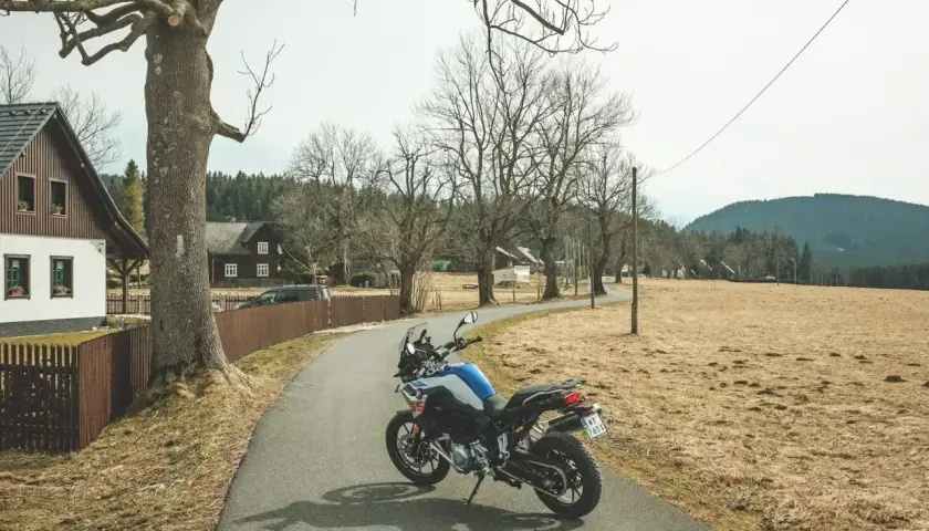 Motocykl na drodze w Czechach, wśród domków i drzew.