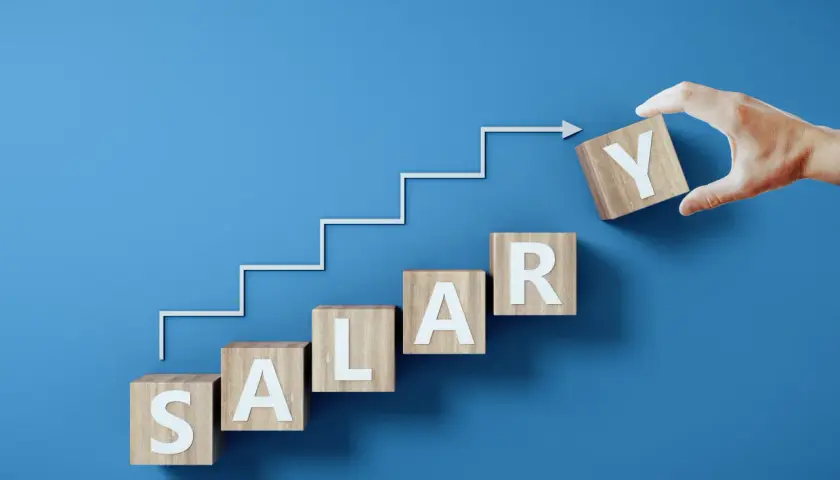 Drewniane klocki z literami tworzą napis SALARY, symbolizując drogę do jawności wynagrodzeń. Krok po kroku, ku lepszemu.