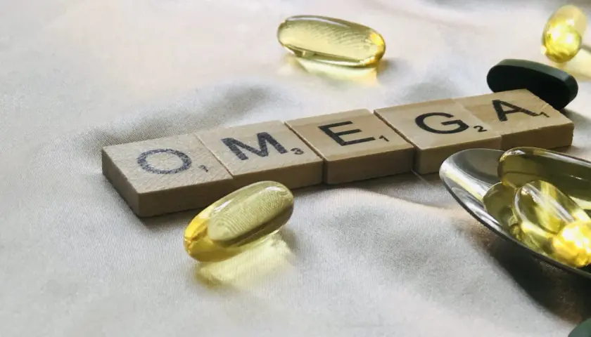 Capsule di olio di pesce e tessere con la scritta OMEGA. Chissà dopo quanto tempo fanno effetto gli omega-3 per il benessere.