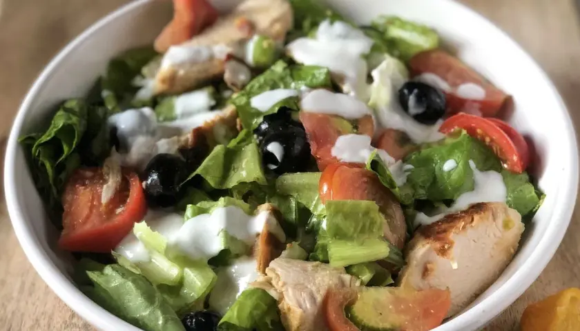 Fresca insalata di pollo con verdure croccanti, pomodori succosi e olive nere, condita con una cremosa salsa.
