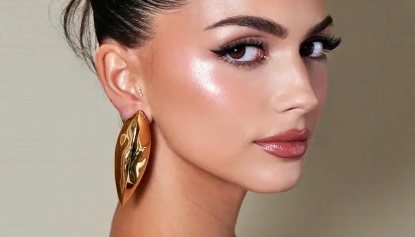 Rostro con maquillaje radiante, destacando el uso de iluminador en barra para un brillo natural.
