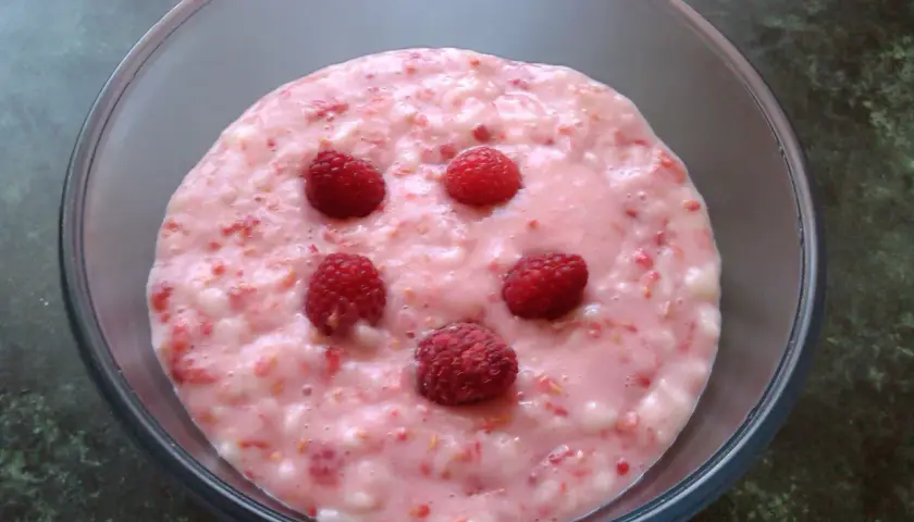 Pyszny budyń malinowy z malinami w szklanej misce.