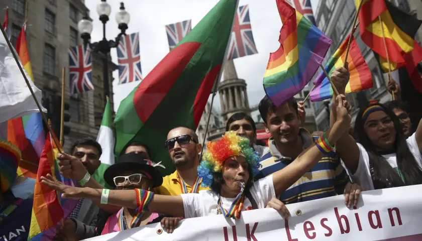 People wave rainbow and national flags at a pride parade, showing why understanding diversity is important for unity and celebration.