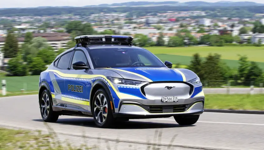 Policyjny Ford Mustang Mach-E z włączonymi sygnałami świetlnymi. Pamiętaj, kiedy można wyprzedzać pojazd uprzywilejowany.