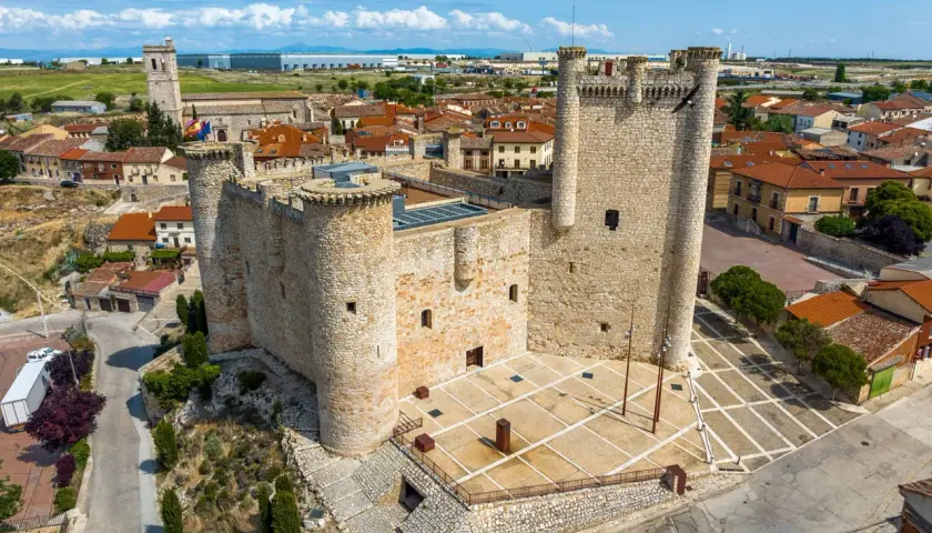 Castillo medieval en un pueblo bonito de Guadalajara, con tejados rojos y cielo azul.