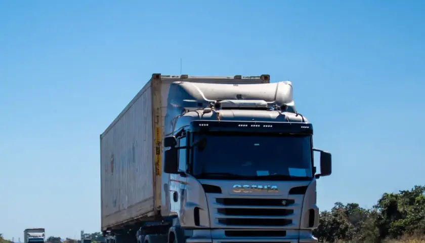 Ciężarówka Scania z kontenerem na autostradzie pod błękitnym niebem.