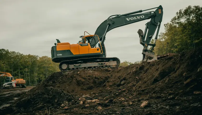 Duża koparka Volvo pracuje na budowie. Zastanawiasz się, ile zarabia operator koparki?