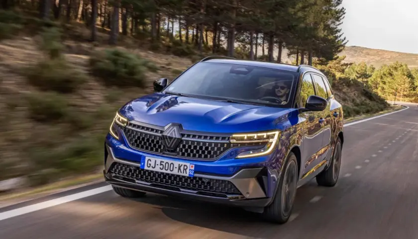 Blå Renault Austral kör på en slingrande väg genom en skog. Inga problem med denna bil, bara ren körglädje.