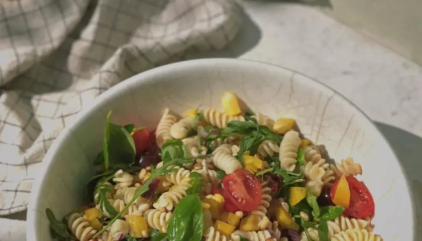Leckerer Weight Watchers mediterraner Pastasalat mit Fusilli, Kirschtomaten, Rucola und gelber Paprika in einer Schüssel.