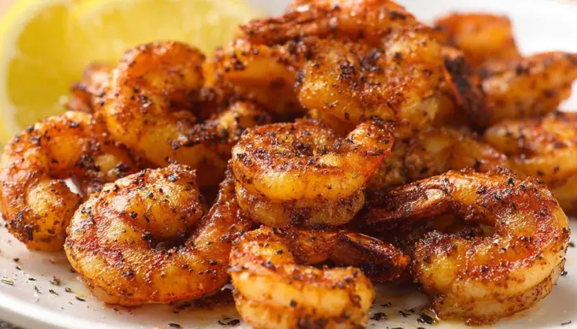 Chrupiące krewetki z airfryer, przyprawione i gotowe do podania z cytryną.