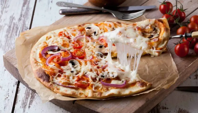 Eine köstliche Pizza mit geschmolzenem Käse, Tomaten, Zwiebeln und Pilzen. Der Teig, wie vom echten Italiener, wurde im Thermomix zubereitet.