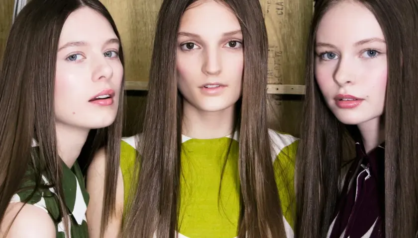 Trzy modelki z długimi włosami, prosto obciętymi, prezentują nowy trend fryzur.