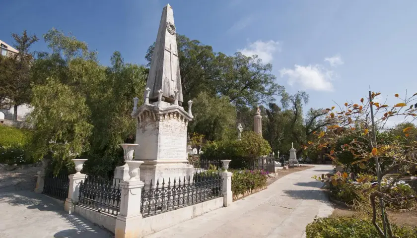 Un obelisco y monumentos se alzan en el cementerio de los ingleses, un lugar sereno bajo un cielo azul.