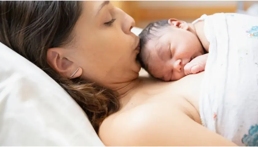 Mamma bacia il suo neonato, un momento di tenerezza che celebra la fine delle 38 settimane di gravidanza, quanti mesi sono circa nove.