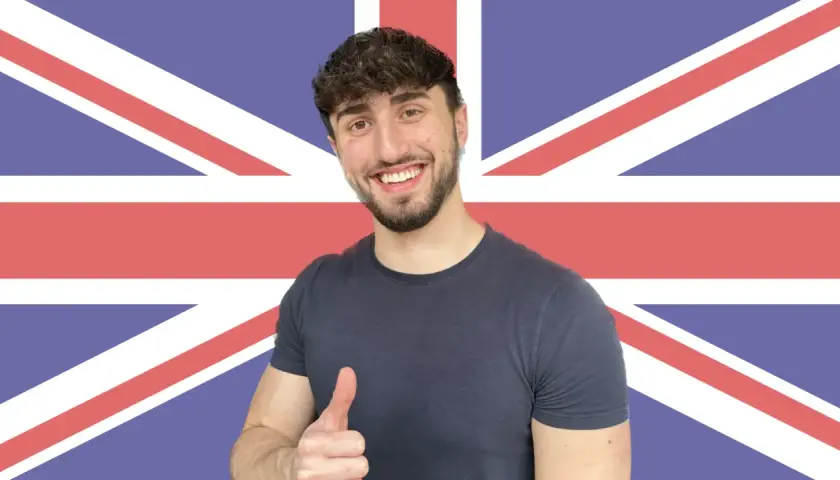 Giovane sorridente con pollice in su, sullo sfondo della Union Jack. Ha deciso di get phrasal verb per imparare l'inglese.