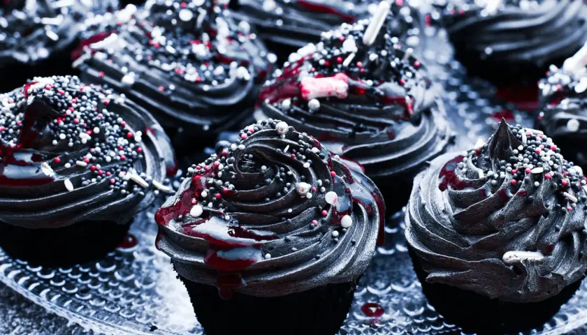 Mroczne muffinki halloween z czarną polewą, czerwonym lukrem i kolorową posypką.
