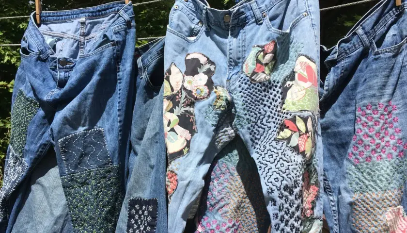 Jeans repaired with colorful patches and intricate stitching, showcasing creative ways how to darn.