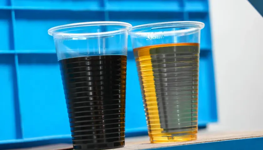 Dwa kubki z płynami: ciemny olej i jasny olej, porównanie stanu po użyciu i nowego. Może to być test filtra oleju skrzyni biegów.