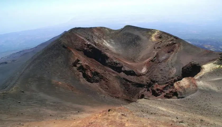 Crateri dell'Etna, un paesaggio lunare da esplorare con la propria auto. Rocce vulcaniche rosse e nere sotto un cielo azzurro.