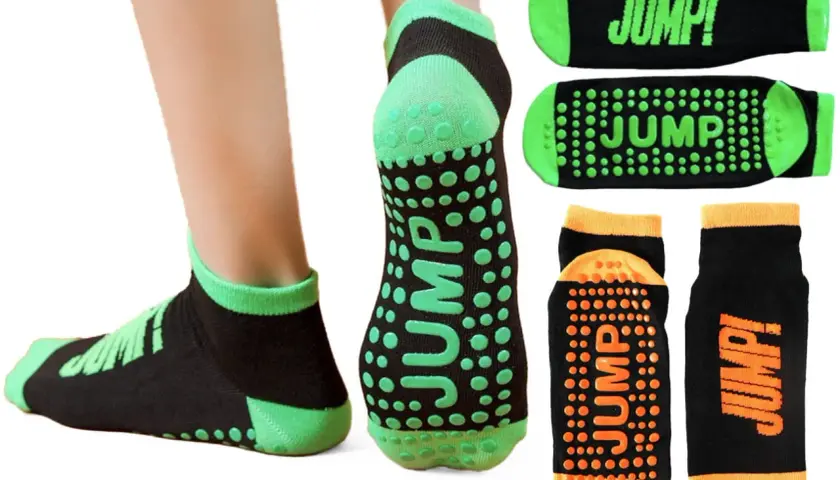 Skarpety sportowe antypoślizgowe z napisem "JUMP!" i zielonymi lub pomarańczowymi wypustkami dla lepszej przyczepności.
