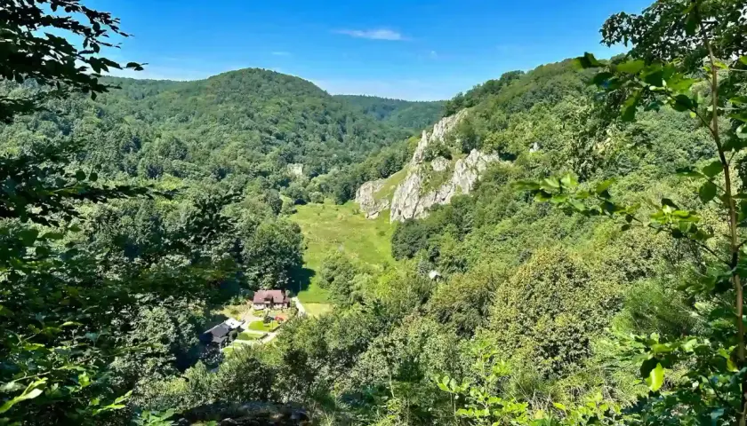 Ojcowski Park Narodowy ciekawostki: malownicza dolina z górami, skałami i domkami.